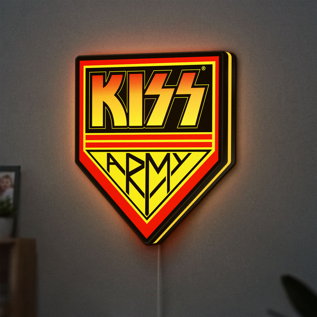 Kiss Army LED lightbox hanging on a wall with yellow glow