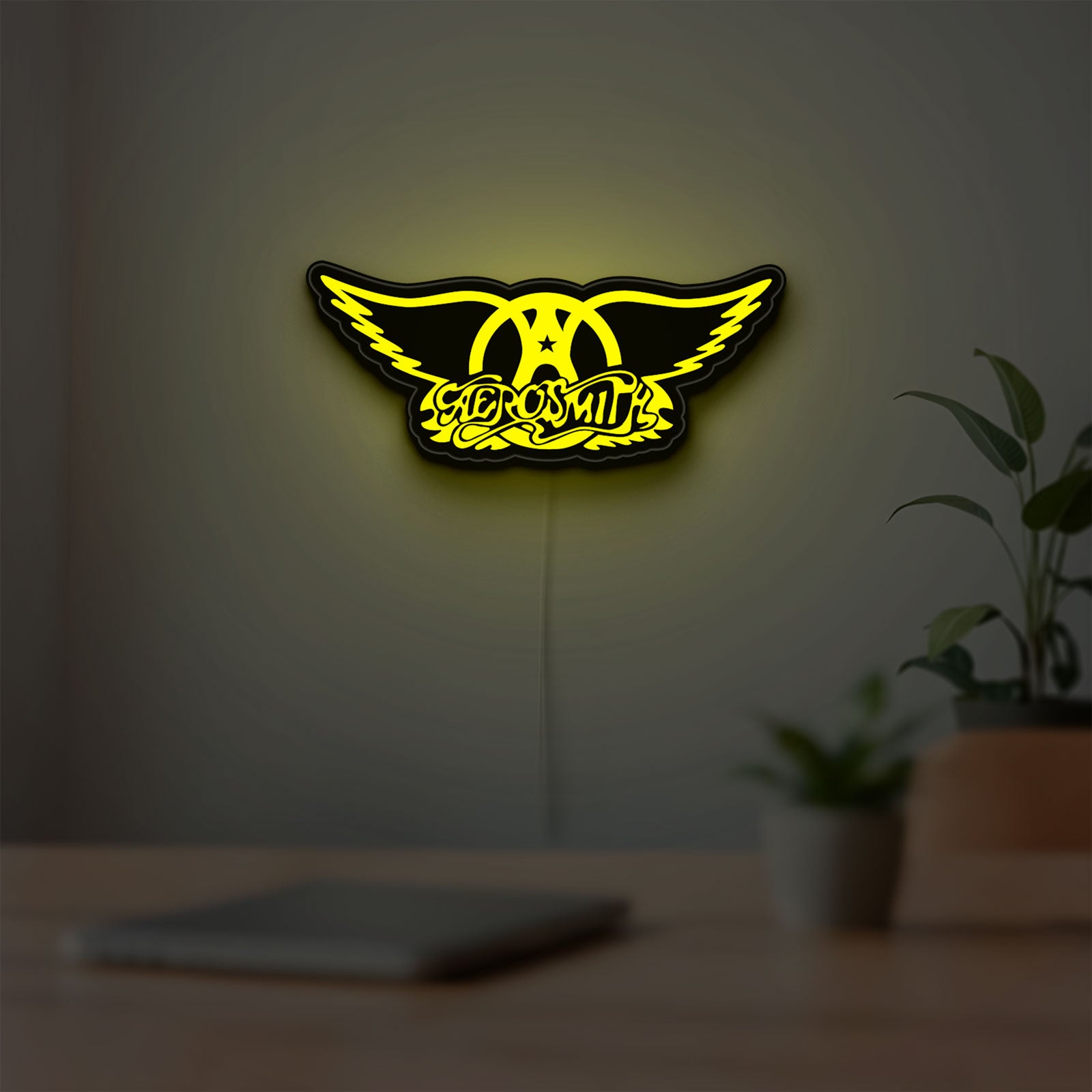 Aerosmith LED lightbox hanging on a room wall with soft yellow light