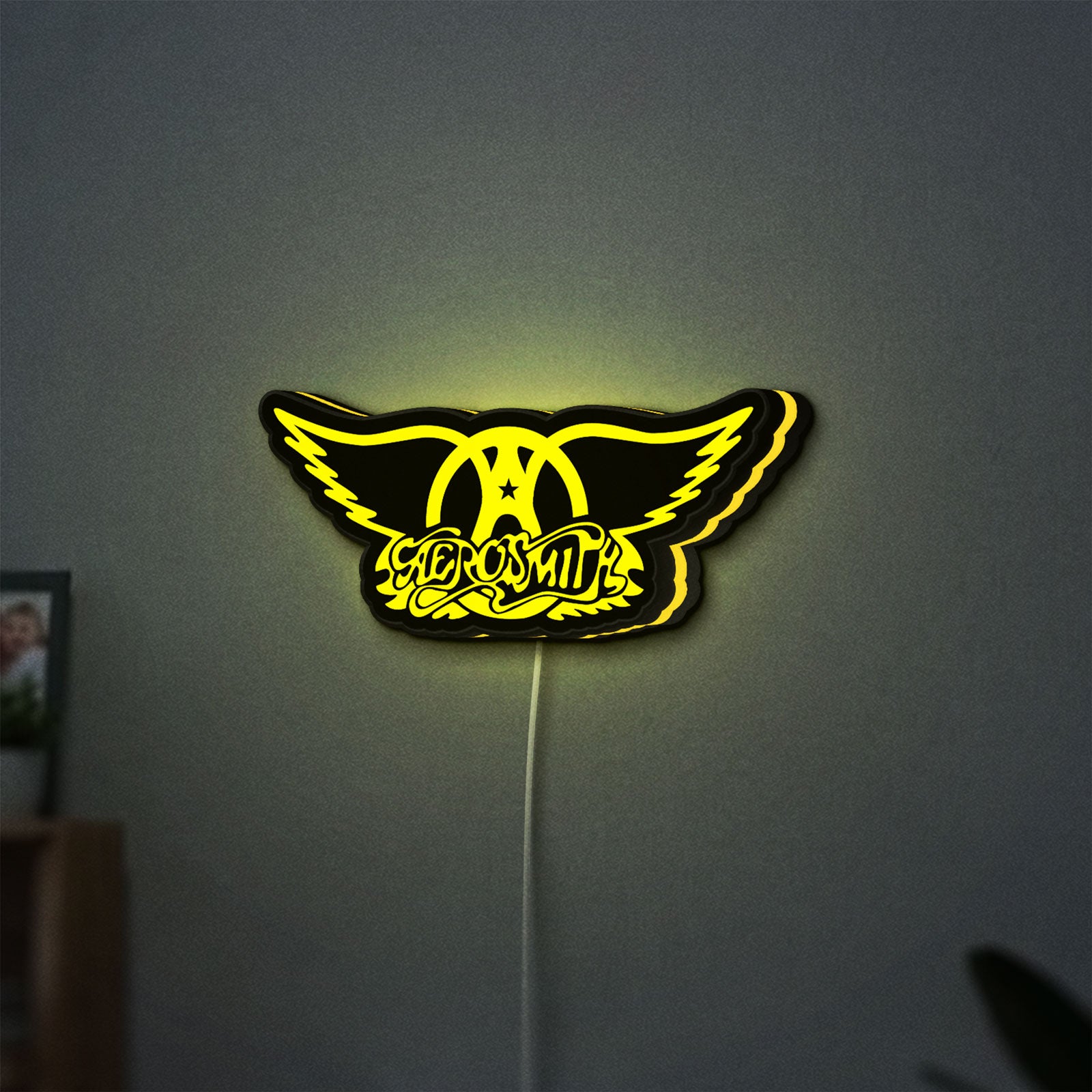 Aerosmith LED lightbox hanging on a wall with yellow glow