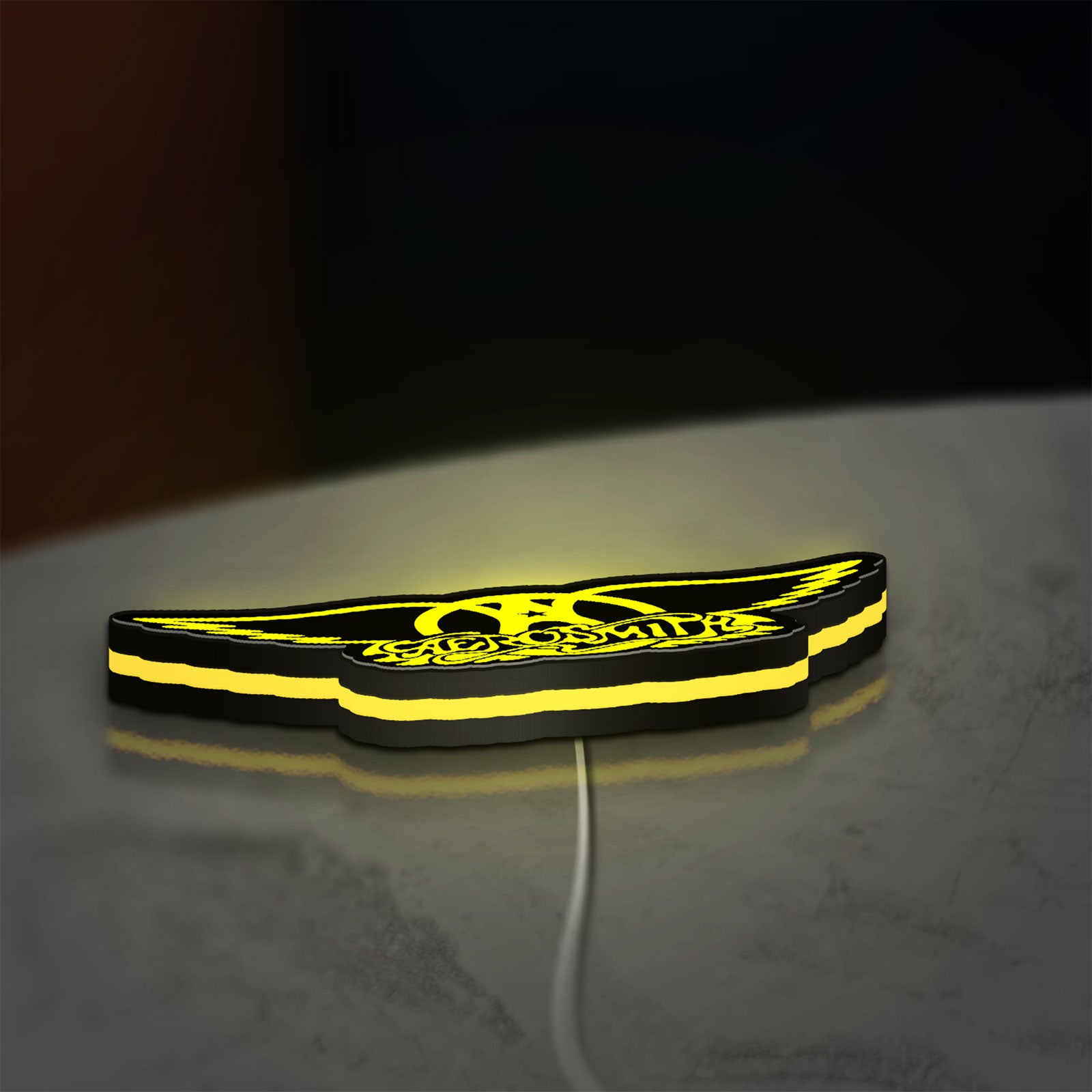 Aerosmith LED lightbox lying flat on a desk with yellow glow