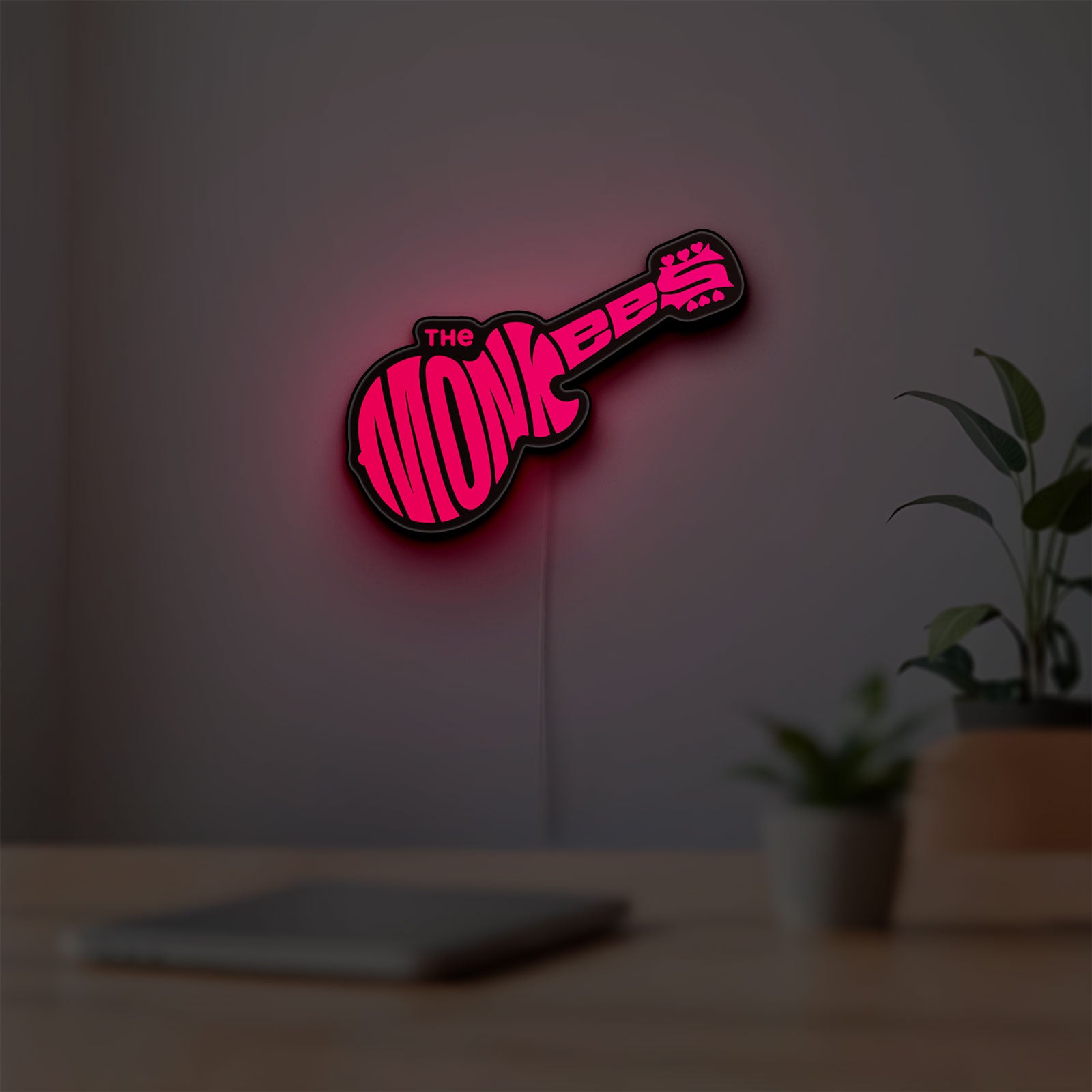 The Monkees Guitar LED lightbox hanging on a room wall with soft red light