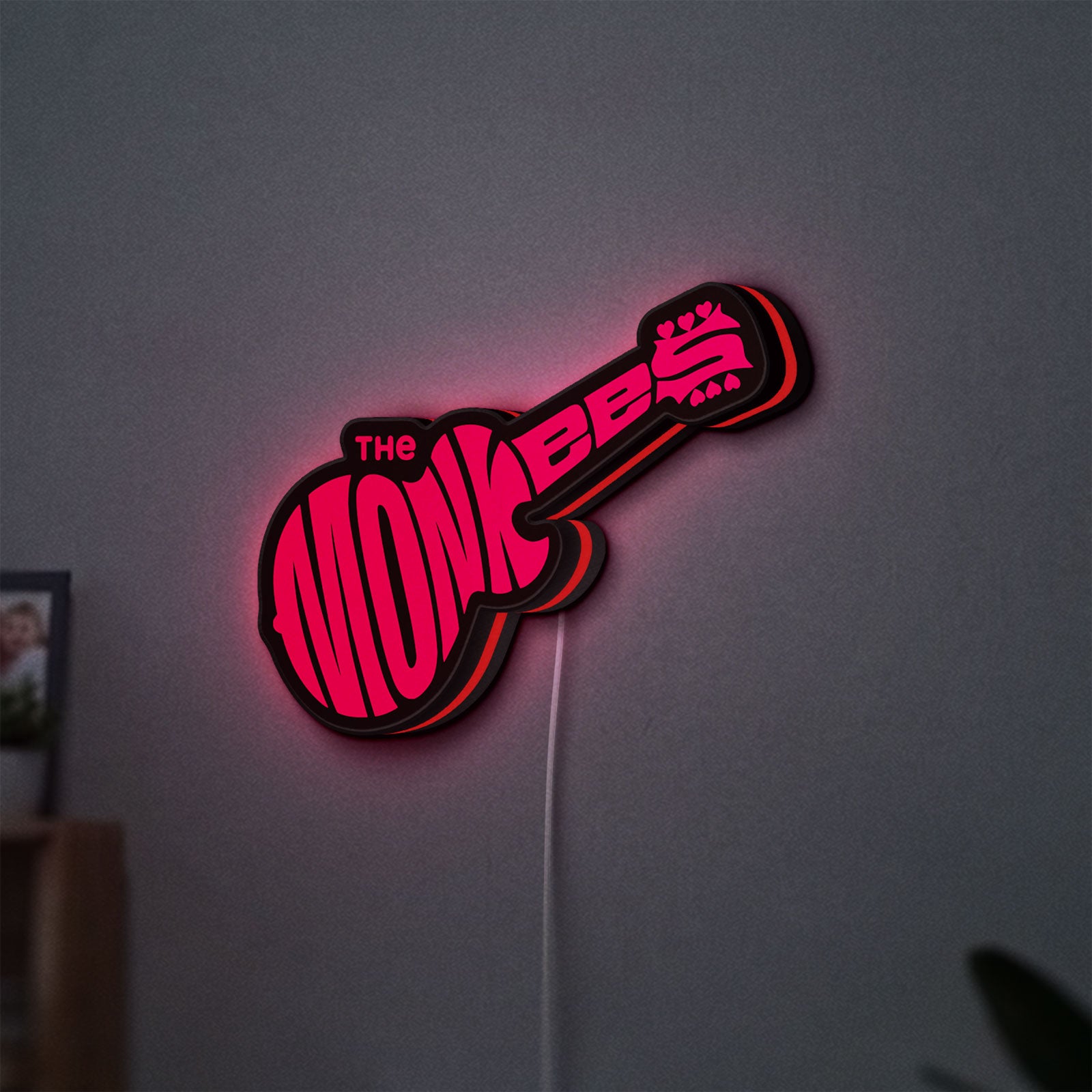 The Monkees Guitar LED lightbox hanging on a wall with red glow