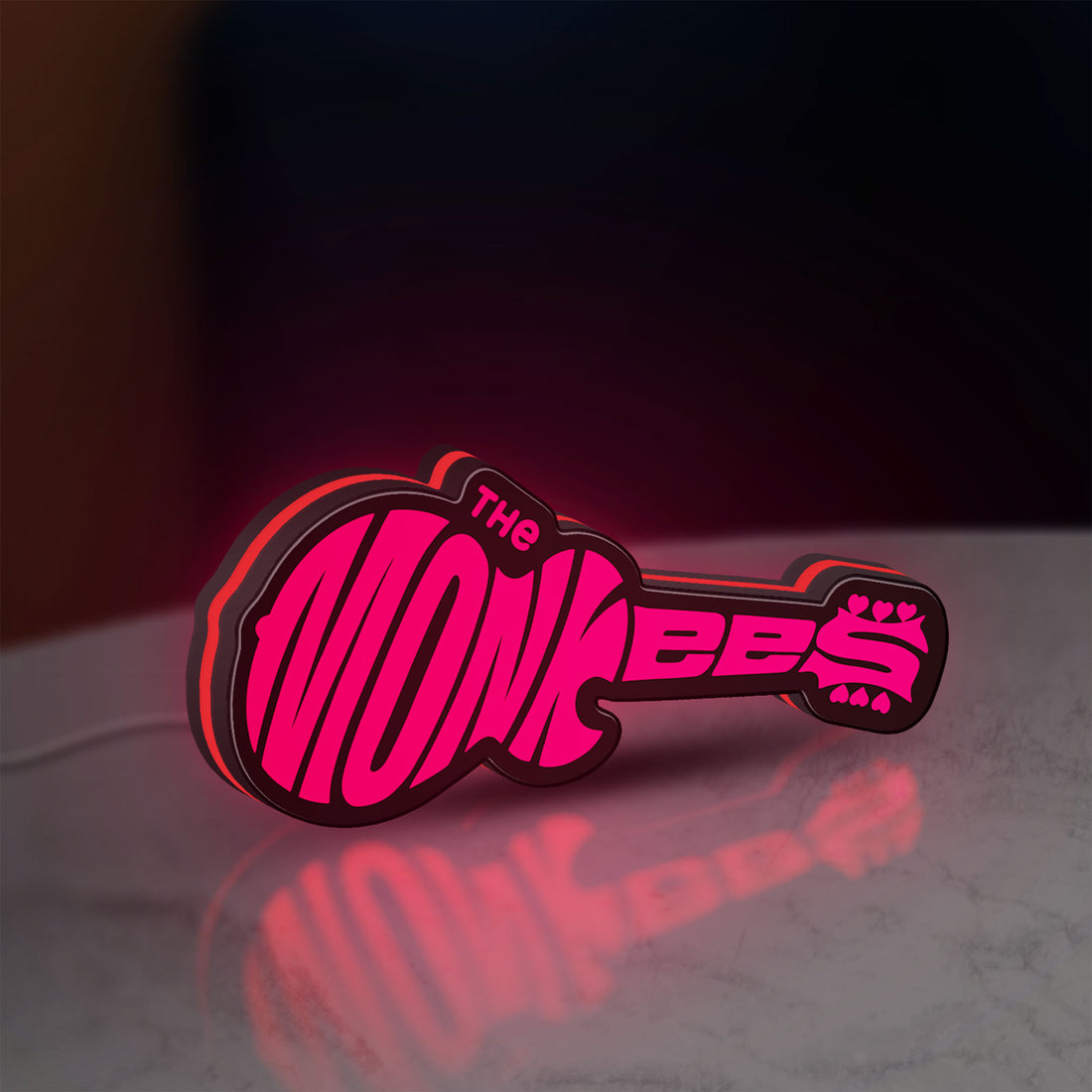 The Monkees Guitar LED lightbox hanging on a wall with red glow