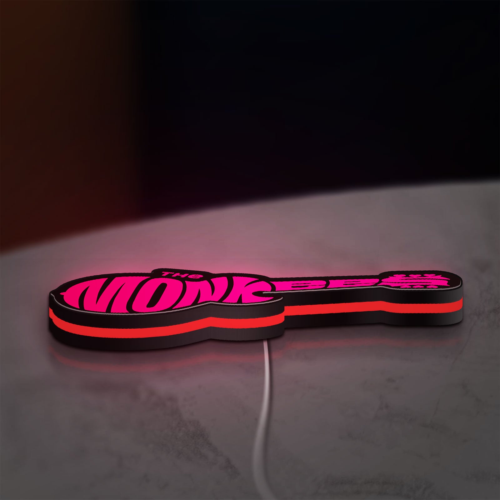 The Monkees Guitar LED lightbox lying flat on a desk with red glow