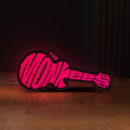 Front view of The Monkees Guitar LED lightbox sign glowing on a wooden desk