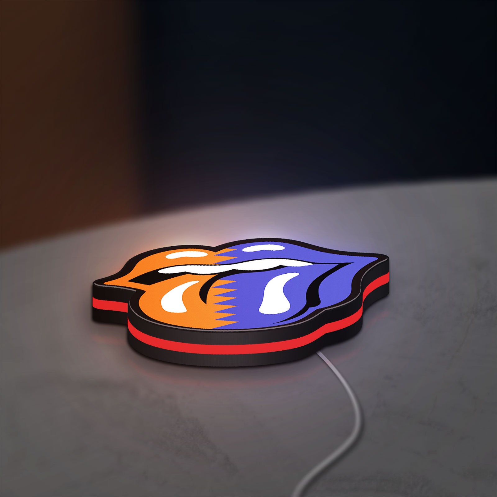 Rolling Stones LED lightbox lying flat on a desk with red glow