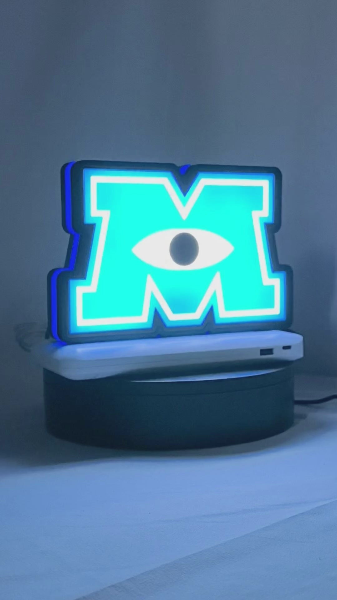 Product video showcase of Monsters University 3D LED Sign, demonstrating unlit and illuminated lighting effects with a 360-degree rotating view, unique wall art for desk and room decor.