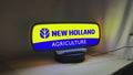 Product video showcase of New Holland Agriculture 3D LED Sign, demonstrating unlit and illuminated lighting effects with a 360-degree rotating view, perfect for garage and man cave decor.