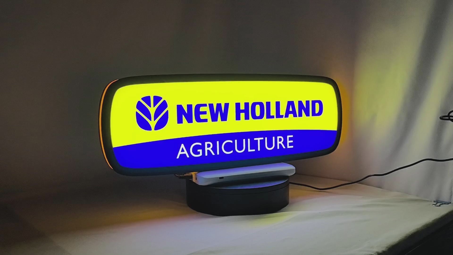 Product video showcase of New Holland Agriculture 3D LED Sign, demonstrating unlit and illuminated lighting effects with a 360-degree rotating view, perfect for garage and man cave decor.